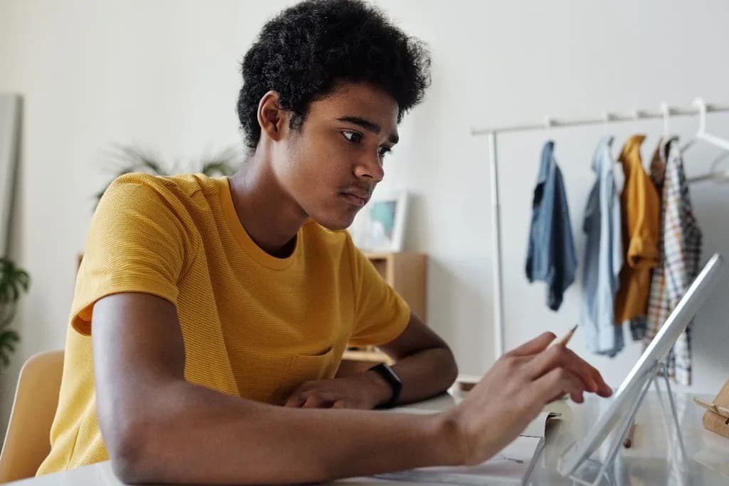 Student in a yellow shirt studying at a desk with a tablet and pencil