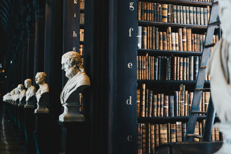 A historic library with bookshelves and marble busts